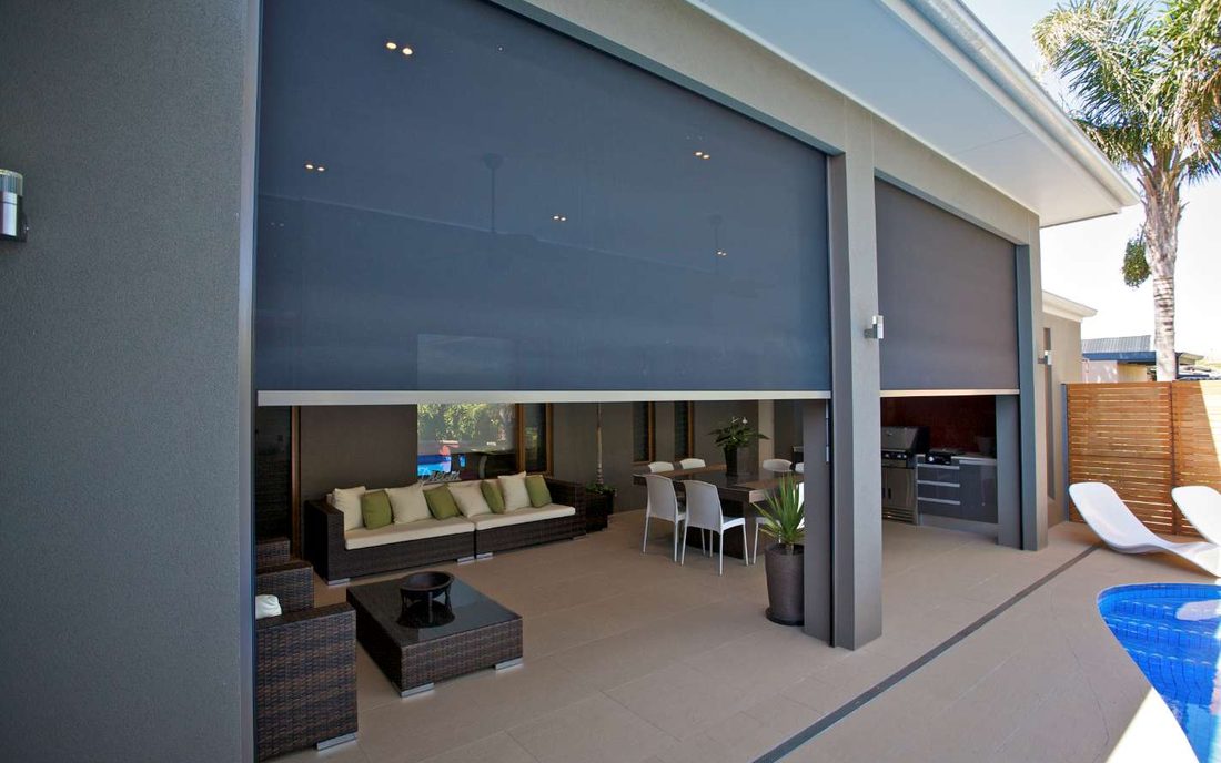 Outdoor blinds down over a furnished alfresco beside a pool